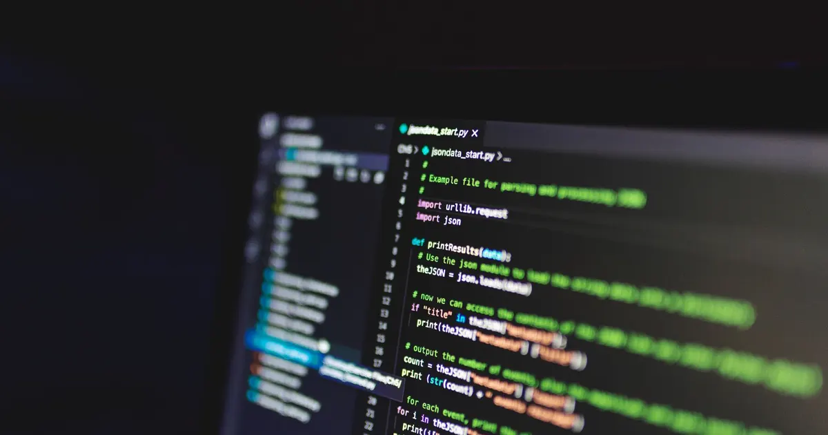 Programming code on a dark computer screen in a dimly lit room
