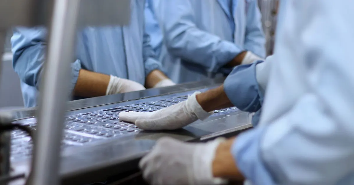 Workers packaging tablets along a pharmaceutical production line